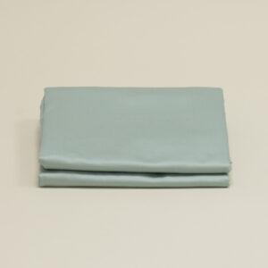 Sateen bed linen in Celadon Green, a grey-green shade, folded in three layers